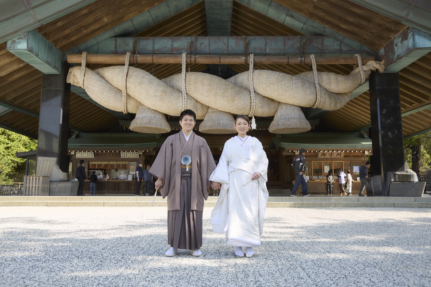 出雲大社結婚式場・神楽殿の大注連縄の前に立つ新郎新婦
